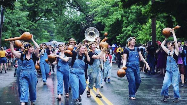 People with instruments dance in the street during the Ithaca Festival Parade