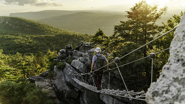 A man walks across a suspension bridge on the new Via Ferrata experience at Mohonk Mountain House