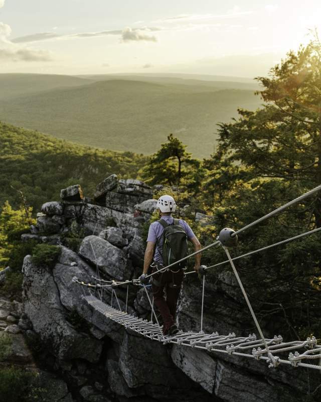 A man walks across a suspension bridge on the new Via Ferrata experience at Mohonk Mountain House