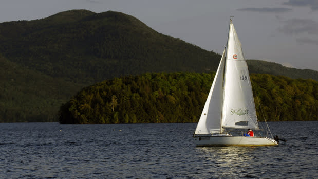 Sailboat in the water with lush greenery and mountains in the background
