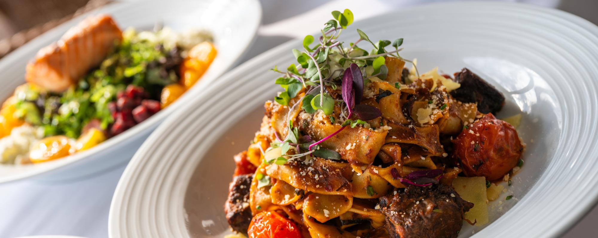 A plate of pasta topped with leafy greens at Sagamore Resort