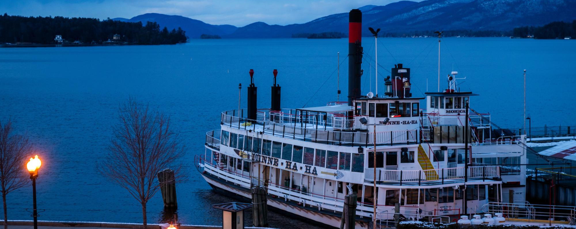 A white steamboat docked at dusk in winter in Lake George